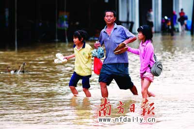 樂(lè)昌市政府前和街道被水浸,一位家長(zhǎng)帶著孩子涉水而行。　　谷立輝童銅韶朱裕超攝
