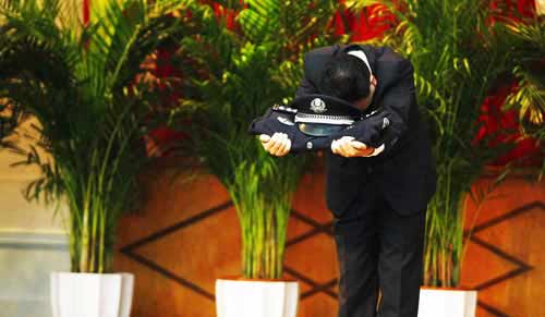 原市局刑警總隊(duì)二支隊(duì)副支隊(duì)長鄭某手托警服警帽向全場鞠躬。圖片來源：重慶晚報(bào)