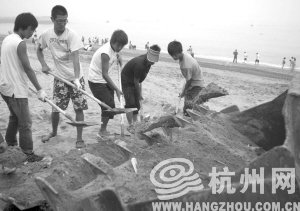 大連市金石灘國賓浴場，工作人員將帶有油污的沙子清理掉。