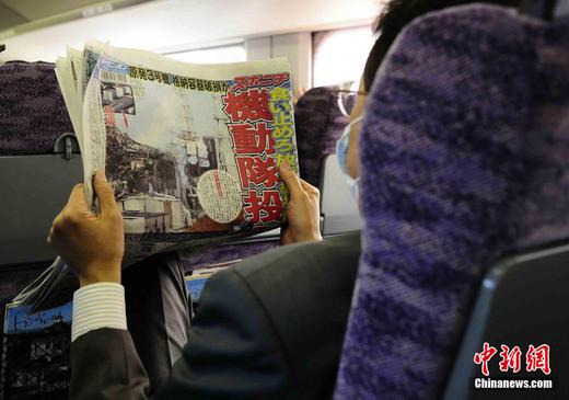 3月17日下午，在一列前往東京的新干線列車上，一名日本人在閱讀關(guān)于福島核電站三號機組最新狀況的報道。中新社發(fā) 侯宇 攝