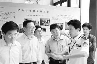 圖為公安部經(jīng)偵局副局長高峰(右)向公安部特邀監(jiān)督員們介紹“亮劍”行動(dòng)展覽情況。 