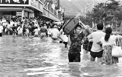 昨日，一名消防戰(zhàn)士在秦皇島市山海關(guān)火車(chē)站站前廣場(chǎng)涉水幫助旅客運(yùn)送行李。 新華社發(fā)