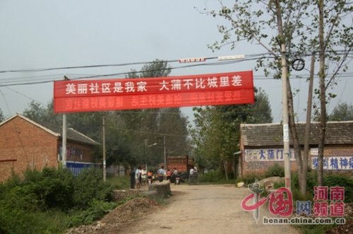 死者的家屬在村口迎接前來(lái)吊唁的親友，紅色的橫幅看上去更具諷刺意味。