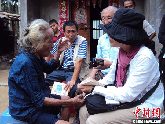 日本“海南島近代史研究會”創(chuàng)始人佐藤正人第22次到海南島調(diào)查日本侵瓊史。圖為在保亭黎族苗族自治縣南林鄉(xiāng)羅葵村，金靜美握著86歲老人林亞金的手。中新社發(fā) 張茜翼 攝