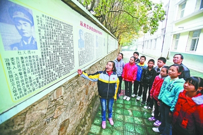 上圖：學校文化墻前，小講解員講述開國將軍杜義德的故事。記者何曉剛 攝