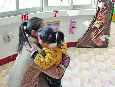 江都商貿(mào)幼兒園一位老師在擁抱該園的孩子。因為涉及收費，作為該園精品教育的一個項目，老師的擁抱行為也被質(zhì)疑。 董鑫 攝
