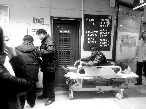 受傷工人小王坐在病床上候診。