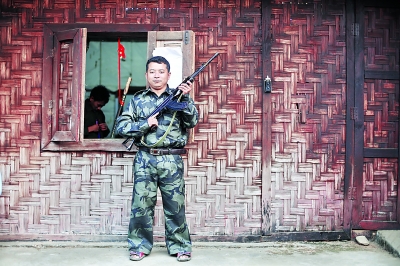 老三手持自己在前線用的半自動(dòng)步槍站在居住的小屋外。