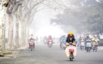 昨天上午，中原路，行人在霧霾中騎車(chē)出行，很多行人戴上了口罩。
