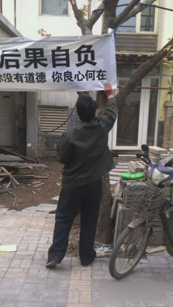 陳成林正在高虎家門(mén)口掛橫幅