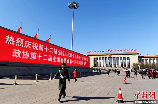 3月4日，北京晴空萬(wàn)里，武警從北京天安門(mén)廣場(chǎng)大型顯示屏前走過(guò)。3月5日上午，十二屆全國(guó)人大一次會(huì)議將隆重開(kāi)幕。中新社發(fā) 劉忠俊 攝