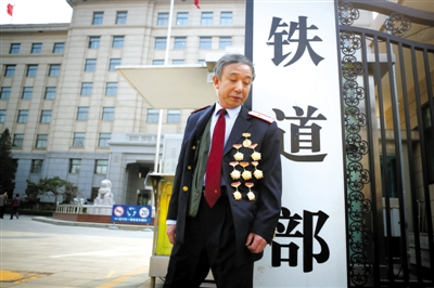 3月14日，鐵道部大門口，一位胸前掛著多枚勛章的鐵道部老職工與鐵道部牌子合影。 新京報記者 侯少卿 攝