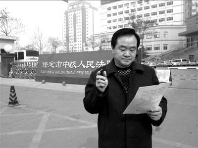 焦占軍在法院門口拿著決定書，無語站立。京華時報記者孫思婭攝
