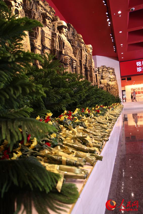 紀(jì)念館門(mén)廳的《銅墻鐵壁》雕塑墻，和人們獻(xiàn)上的花。邱越攝